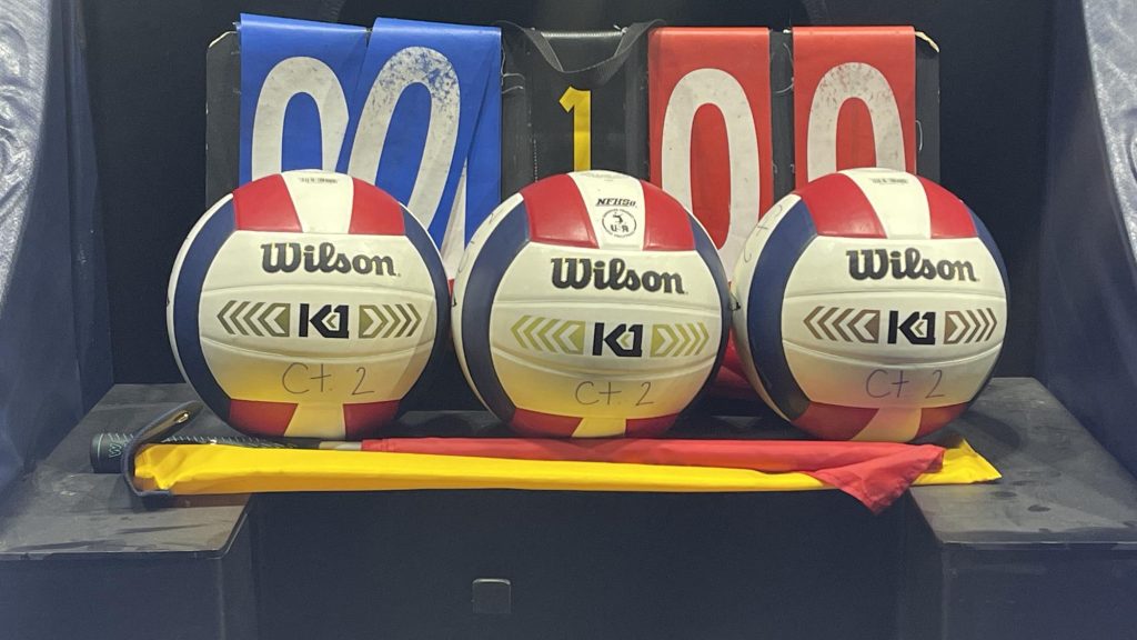Three volleyballs, hand-operated scoreboard and linesmen flags.