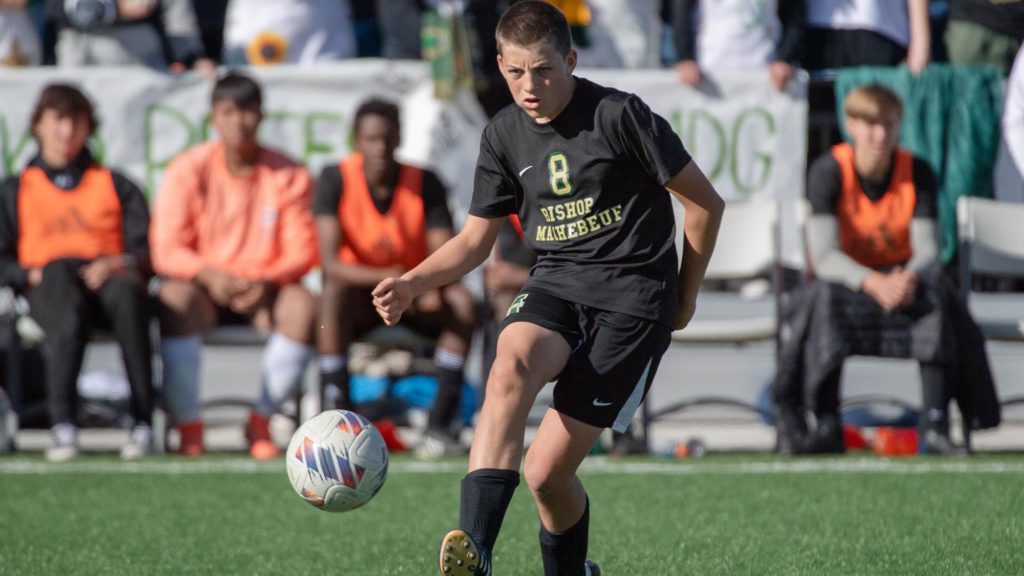 Dominic Siegel of Bishop Machebeuf passes the ball in a boys soccer game.