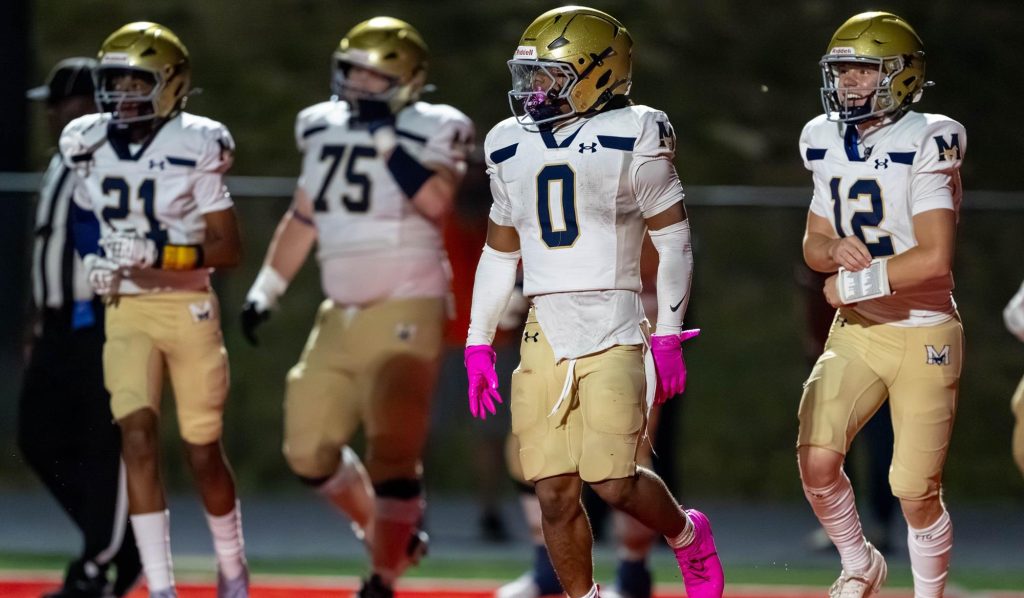 Four Mullen football players walking onto the field